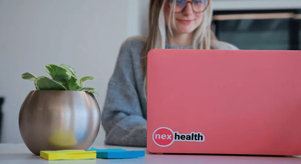 nexhealth culture, nexhealth employee with a laptop, nexhealth sticker